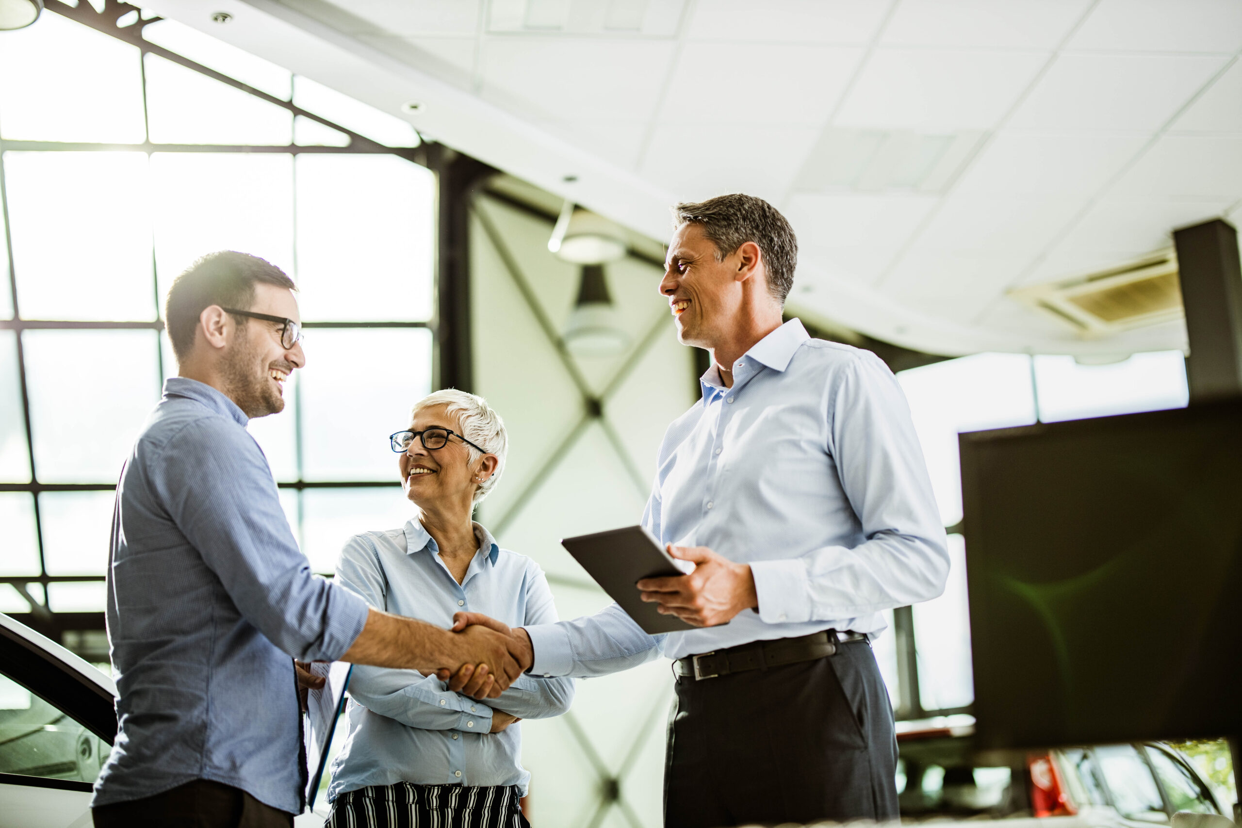 Business colleagues came to an agreement with car salesperson in a showroom